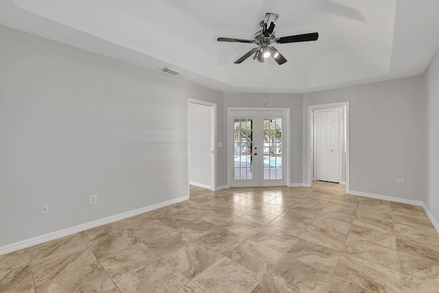 spare room with french doors, a tray ceiling, and ceiling fan