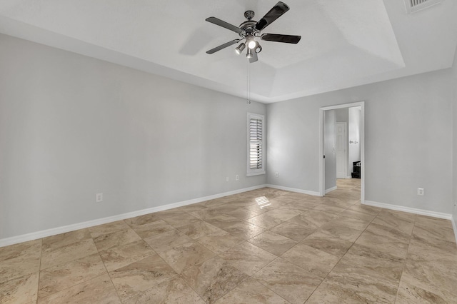 spare room featuring ceiling fan and a raised ceiling