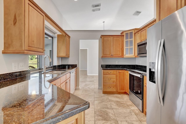 kitchen with dark stone countertops, sink, light tile patterned floors, and stainless steel appliances