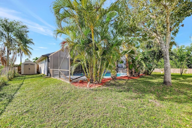 view of yard featuring a fenced in pool, glass enclosure, and a storage shed