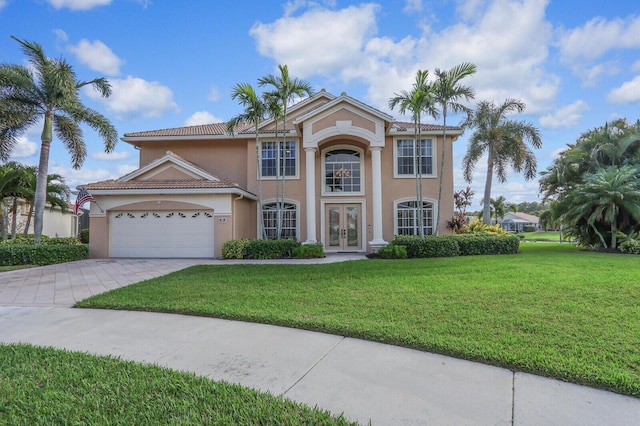 mediterranean / spanish-style home featuring an attached garage, decorative driveway, french doors, a front yard, and stucco siding