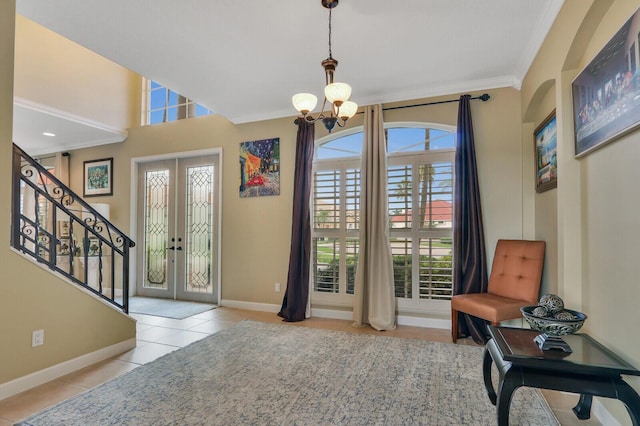 tiled entrance foyer with french doors, stairway, ornamental molding, a chandelier, and baseboards