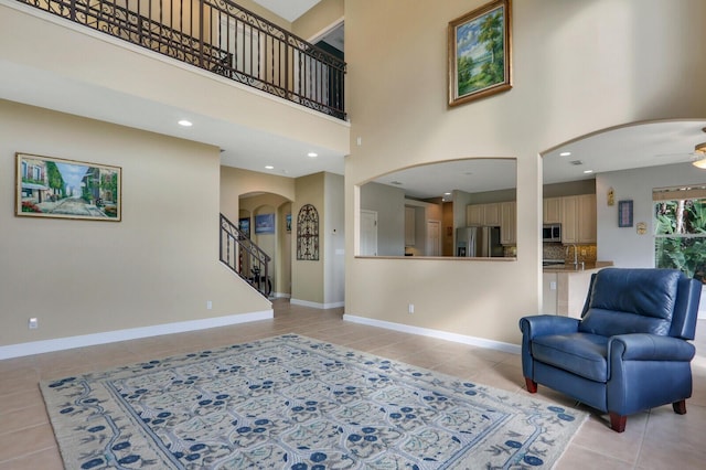 living room with light tile patterned flooring, a towering ceiling, and baseboards