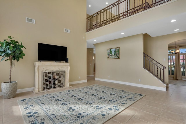 tiled living area featuring arched walkways, stairway, visible vents, and baseboards