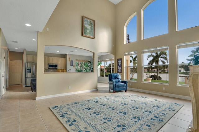 sitting room with light tile patterned floors, recessed lighting, arched walkways, and baseboards