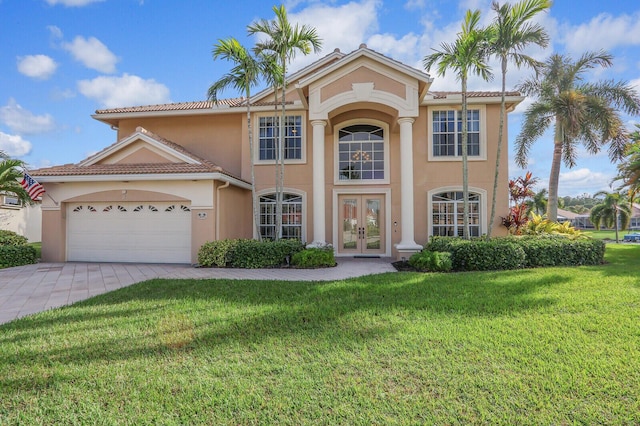 mediterranean / spanish-style house featuring an attached garage, french doors, decorative driveway, stucco siding, and a front lawn