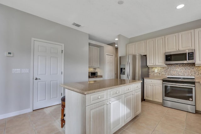 kitchen with appliances with stainless steel finishes, a center island, backsplash, and light tile patterned floors