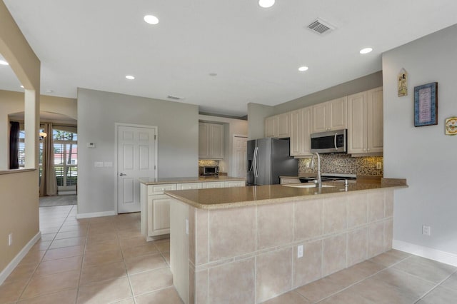 kitchen featuring light tile patterned floors, stainless steel appliances, tasteful backsplash, visible vents, and a peninsula