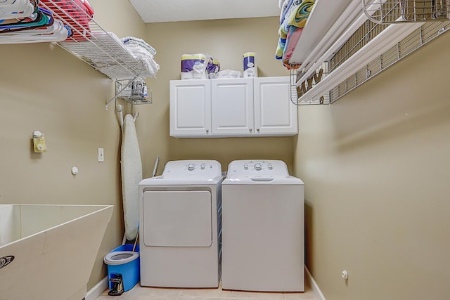 laundry room with washer and clothes dryer, a sink, cabinet space, and baseboards