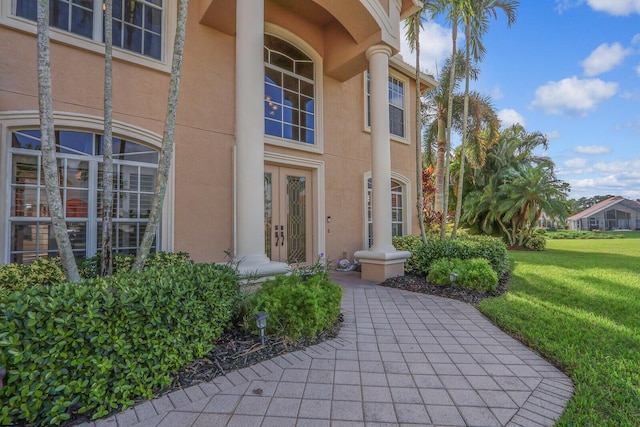 doorway to property featuring french doors, a yard, and stucco siding