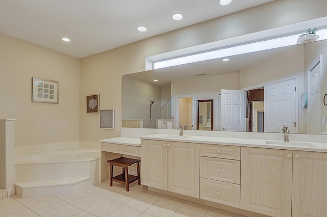 bathroom with a garden tub, double vanity, walk in shower, and a sink