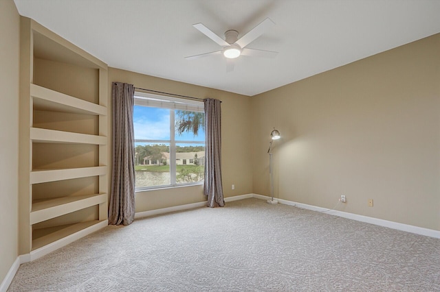 carpeted spare room with a ceiling fan and baseboards