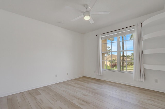 empty room featuring ceiling fan, light wood-type flooring, and baseboards