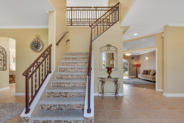 staircase with baseboards, tile patterned flooring, arched walkways, and crown molding