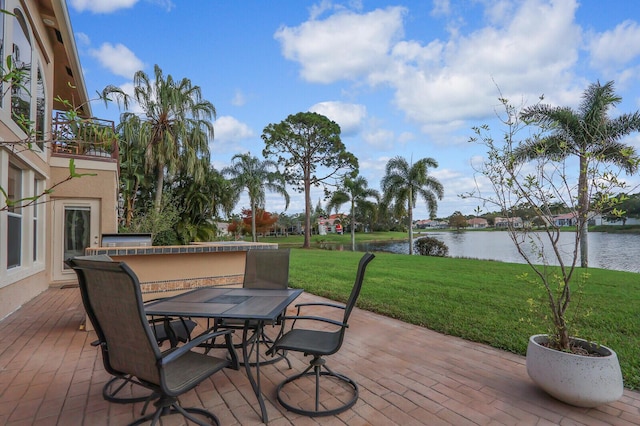 wooden deck featuring outdoor dining area, a water view, a yard, and a patio