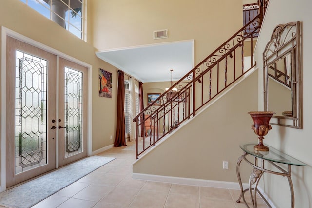 tiled entryway with stairway, french doors, visible vents, and a towering ceiling