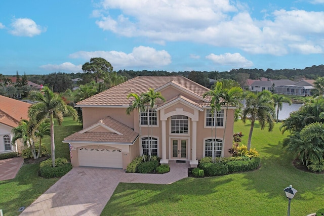 mediterranean / spanish-style house featuring french doors, a tile roof, stucco siding, a front yard, and driveway