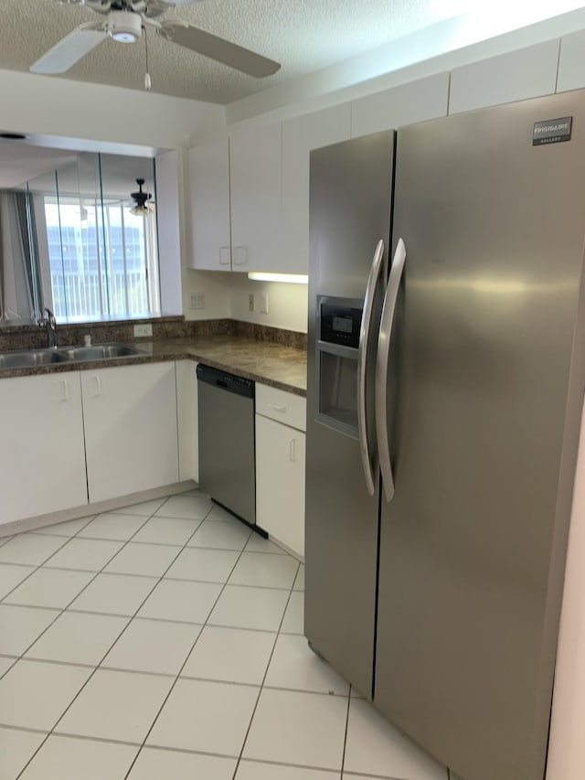 kitchen featuring appliances with stainless steel finishes, sink, light tile patterned floors, and white cabinets