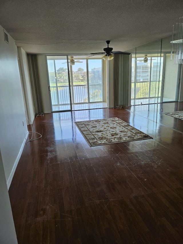 unfurnished room with ceiling fan, dark wood-type flooring, and a textured ceiling