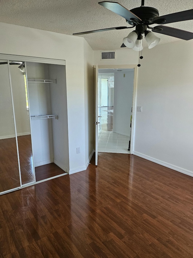 unfurnished bedroom featuring hardwood / wood-style flooring, a closet, ceiling fan, and a textured ceiling