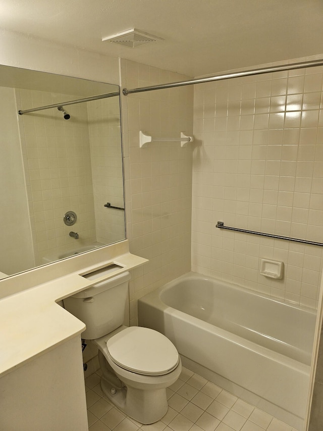 bathroom featuring tile patterned flooring, tiled shower / bath, and toilet