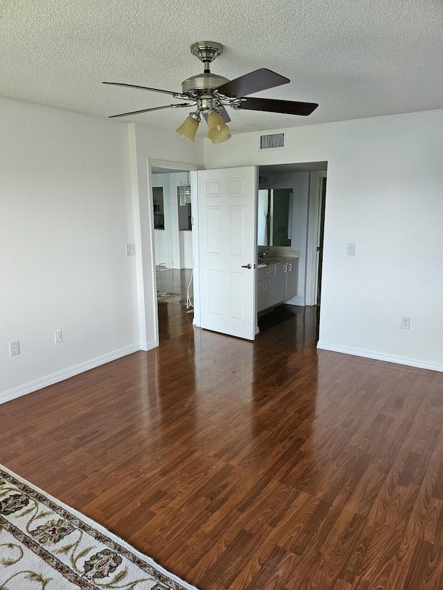 empty room with dark wood-type flooring, ceiling fan, and a textured ceiling