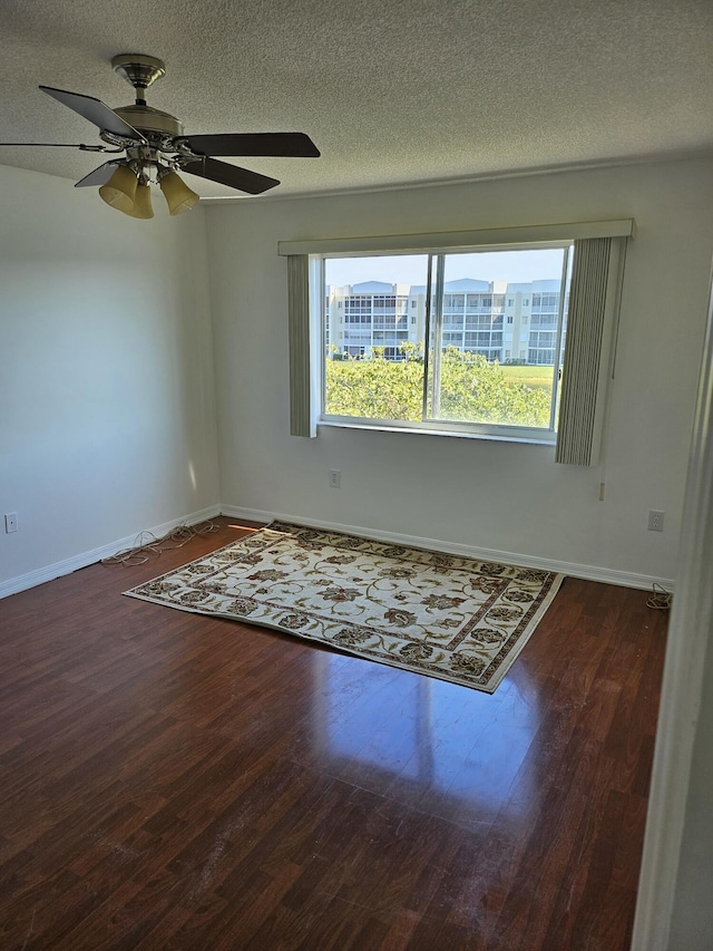 spare room with dark hardwood / wood-style flooring, ceiling fan, and a textured ceiling