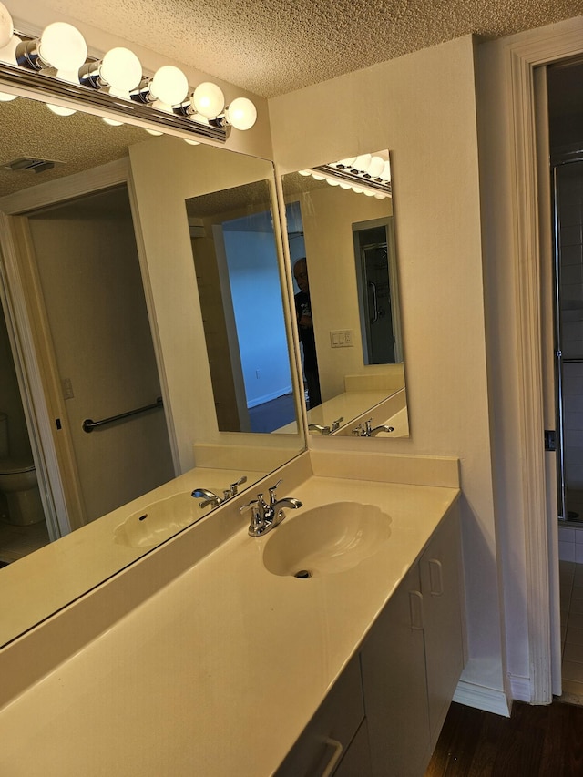 bathroom featuring vanity, toilet, hardwood / wood-style floors, and a textured ceiling