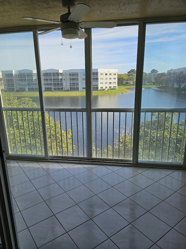 unfurnished sunroom featuring ceiling fan and a water view