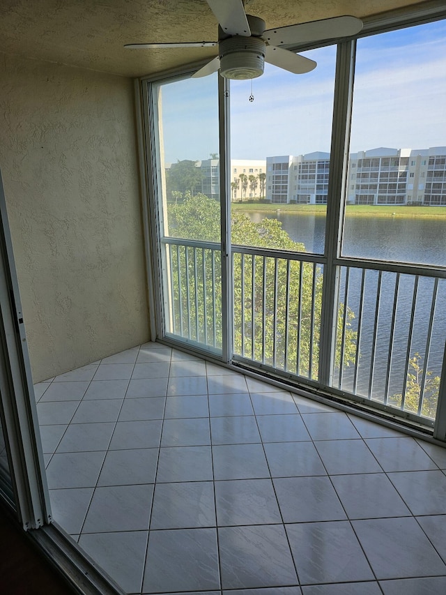 unfurnished sunroom with ceiling fan and a water view