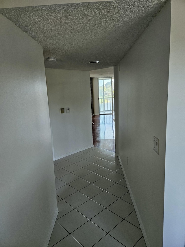 hall with tile patterned floors and a textured ceiling