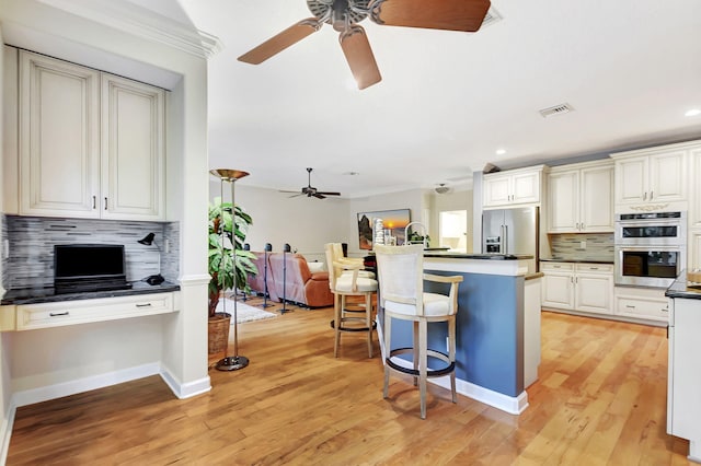 kitchen with a kitchen breakfast bar, light wood-type flooring, tasteful backsplash, and stainless steel appliances