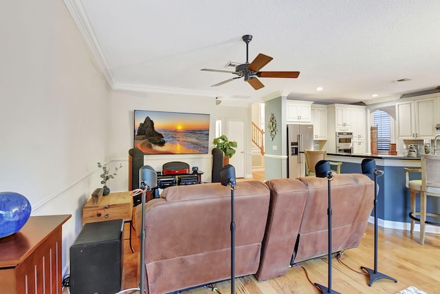 living room with ceiling fan, light hardwood / wood-style floors, and crown molding