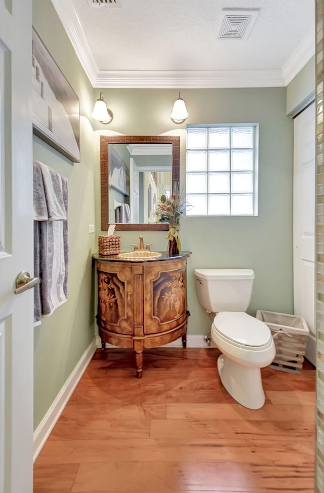 bathroom featuring vanity, hardwood / wood-style flooring, toilet, and crown molding