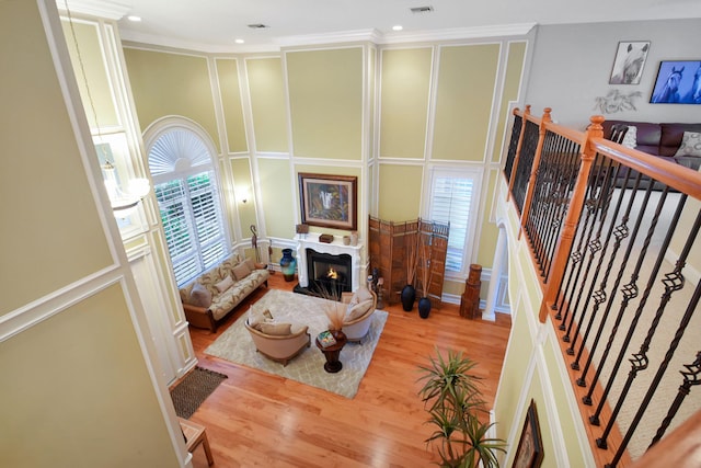 living room with light hardwood / wood-style floors, ornamental molding, and a high ceiling