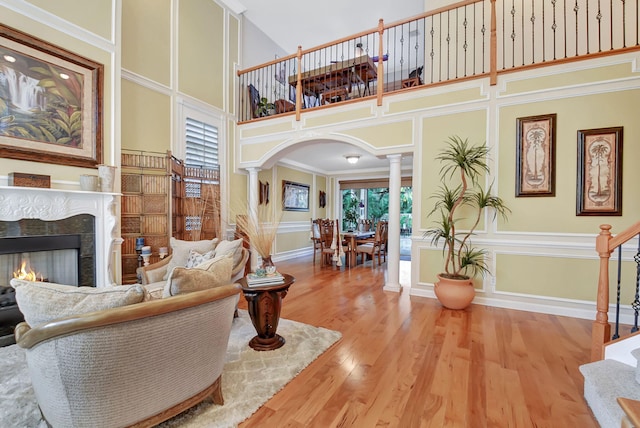 living room with a towering ceiling, decorative columns, hardwood / wood-style flooring, and ornamental molding