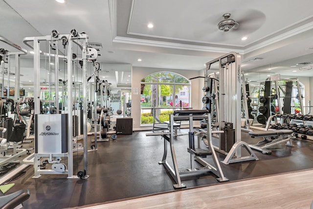 workout area featuring a tray ceiling, ceiling fan, and ornamental molding