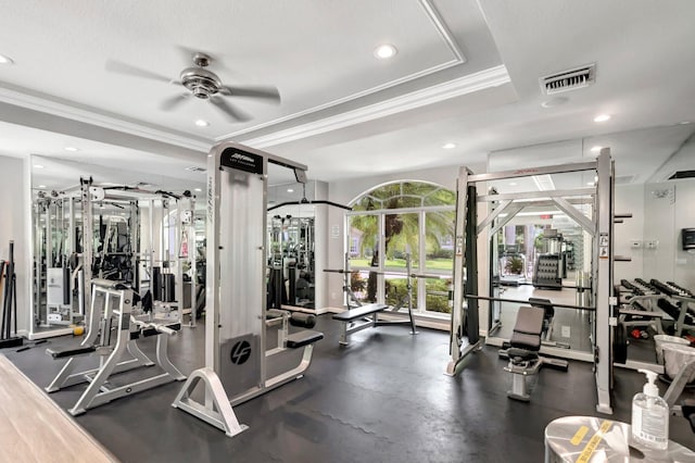 gym with ceiling fan, a raised ceiling, and ornamental molding