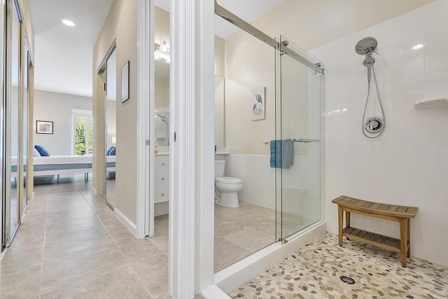 bathroom with tile patterned floors, toilet, and a shower with door