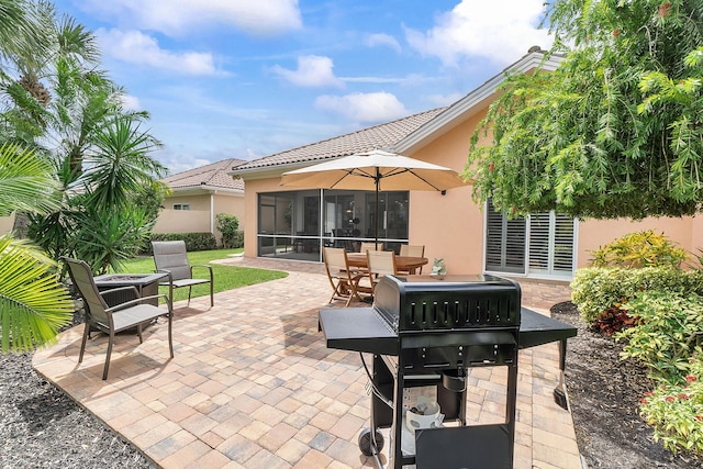 view of patio with area for grilling and a sunroom