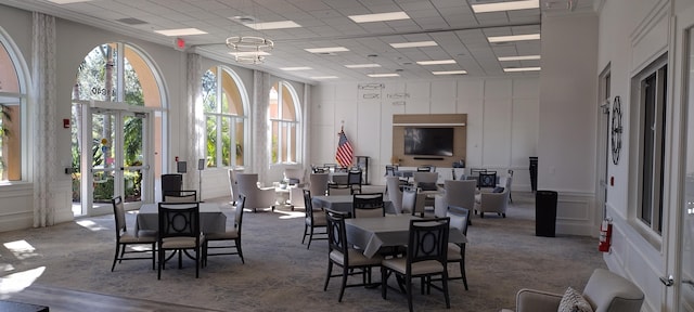 dining room featuring a towering ceiling, a wealth of natural light, and a paneled ceiling