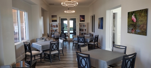 dining area featuring a notable chandelier, crown molding, dark wood-type flooring, and french doors