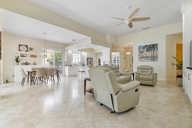 tiled living room featuring ceiling fan with notable chandelier