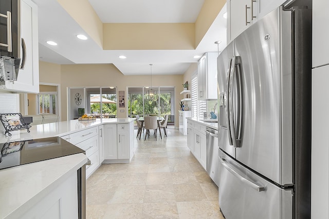 kitchen featuring stainless steel appliances, kitchen peninsula, white cabinets, and decorative light fixtures