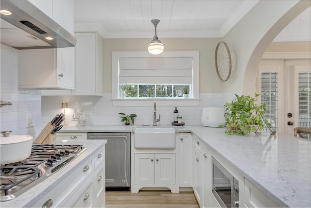 kitchen featuring white cabinetry, sink, stainless steel appliances, hanging light fixtures, and exhaust hood