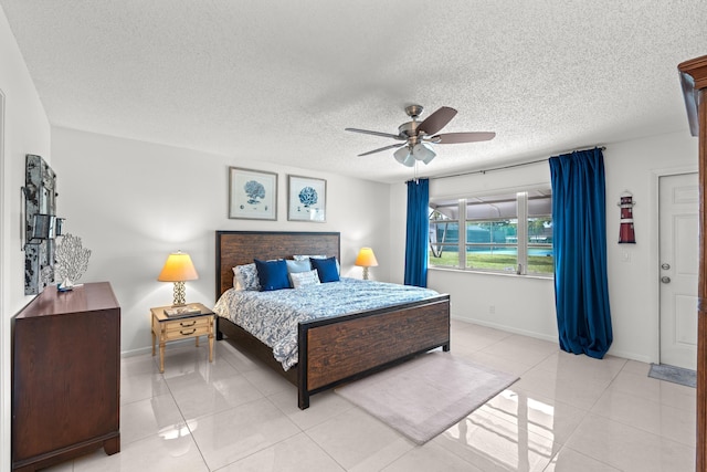 bedroom with ceiling fan, light tile patterned floors, and a textured ceiling