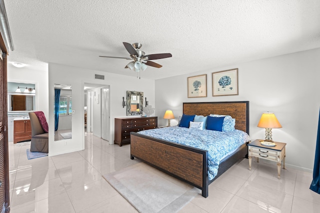 bedroom featuring ceiling fan, light tile patterned floors, a textured ceiling, and ensuite bath