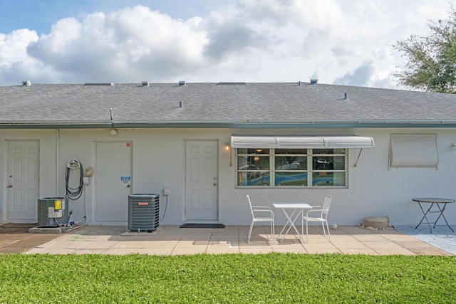 back of property with cooling unit, a patio area, and a yard