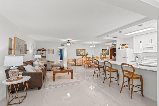 tiled living room featuring ceiling fan, sink, and a textured ceiling