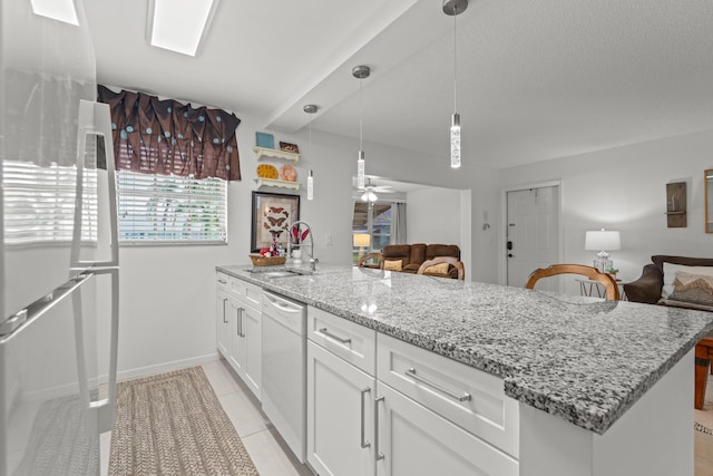 kitchen with white appliances, sink, light tile patterned floors, decorative light fixtures, and white cabinetry